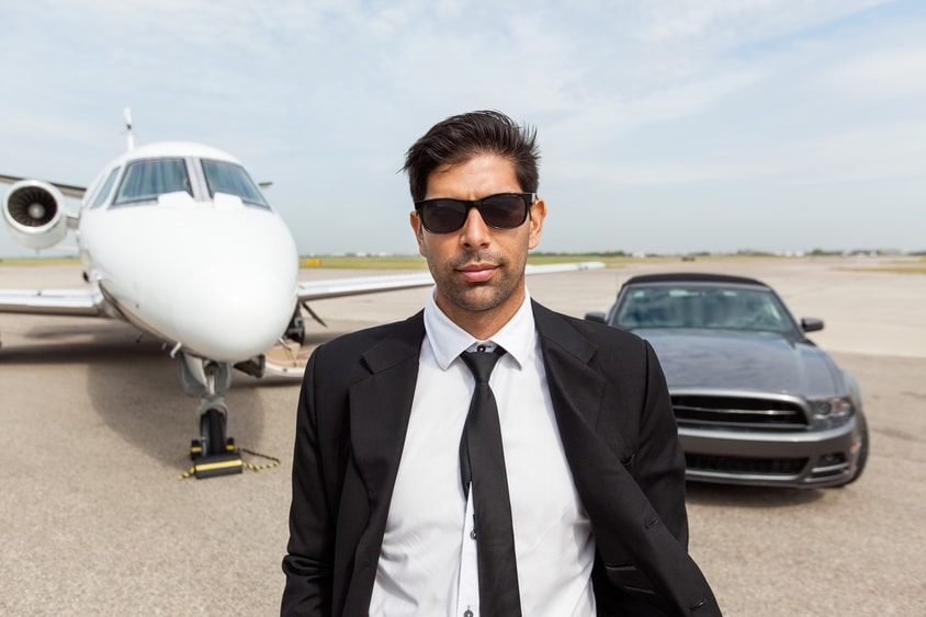 Man in sunglasses standing in front of private plan and a luxury car. Celebrity divorces are private.