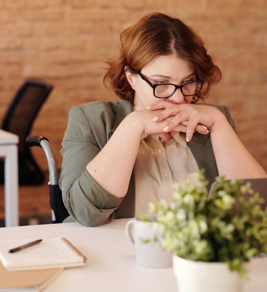 Pensive woman with shorthair and glasses staring at a laptop screen