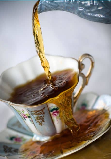 China teacup overflowing as too much tea is poured into it.