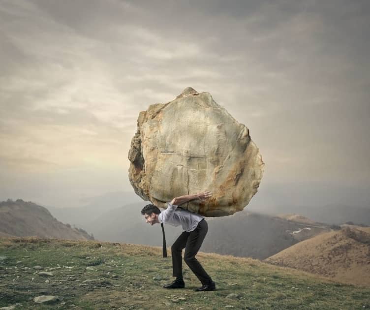 Man carrying a gigantic bolder on his back. Hard work.