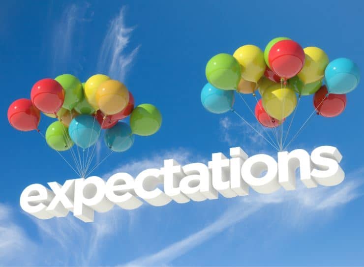 The word "expectations" attached to two bunches of balloons floating upwards in a blue sky.