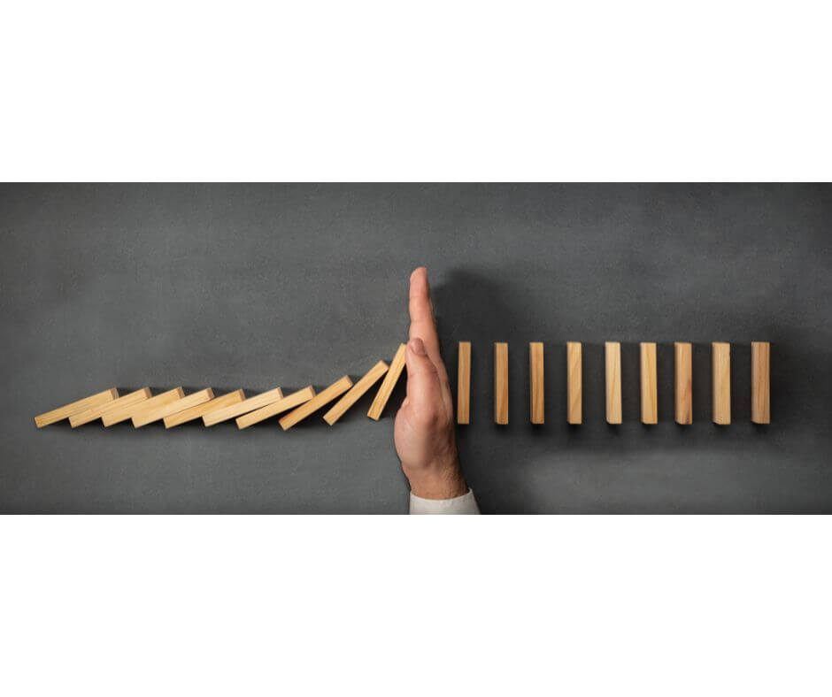Hand stopping a lin of dominoes from being knocked down. Healthy boundaries.