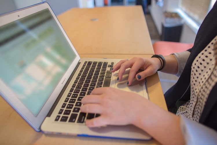 woman's hands typing on a computer keyboard.