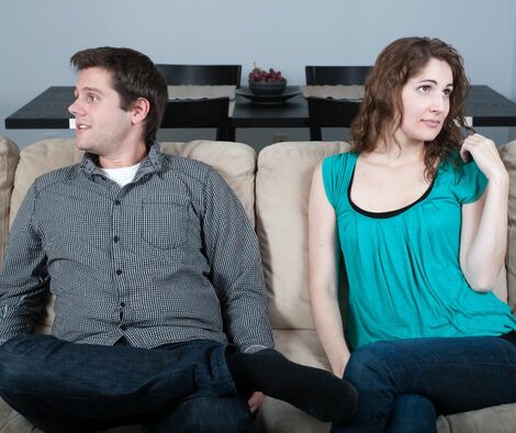 Couple having a boring date on a coach not looking at each other.