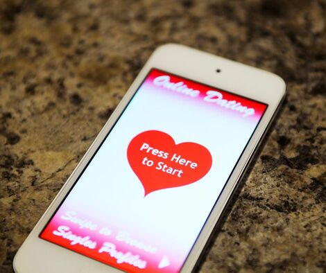 cell phone with online dating app in a heart on it.