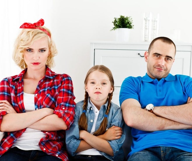 Un happy family of mom, dad and daughter looking at the camera with disdain.