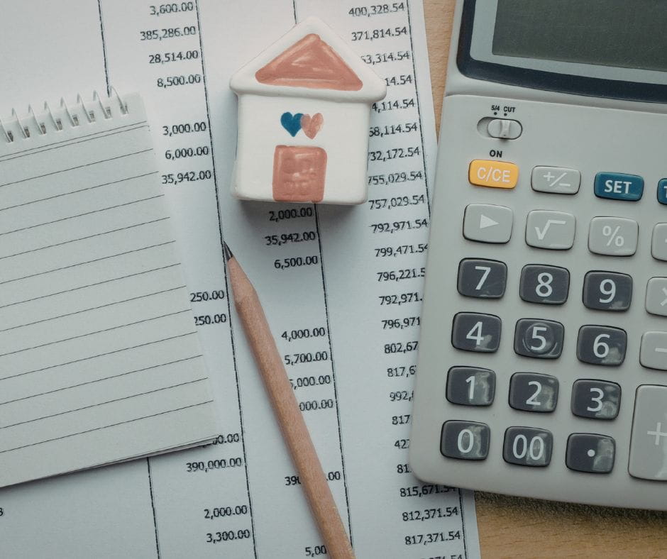 Budget, pencil, calculator and small ceramic house signifying having a financial plan.
